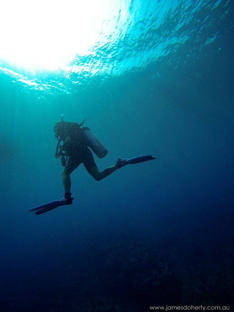 Diver hanging in crystal clear blue water.